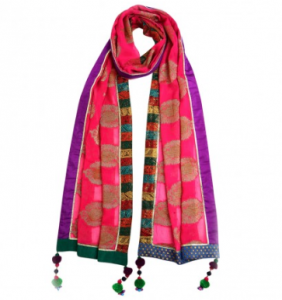 This lurex yarn brocade scarf features a solid border with pom pom tassels. Made of poly georgette. This is a festive scarf for the artist in all of us. This is an exclusive small run and handmade piece from local artisans. In rich hues of pink and gold, bordered by bright purple, green and blue.